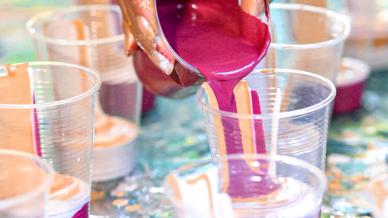 Fluid acrylic mixed with flow medium and metallic pigment pouring across a canvas